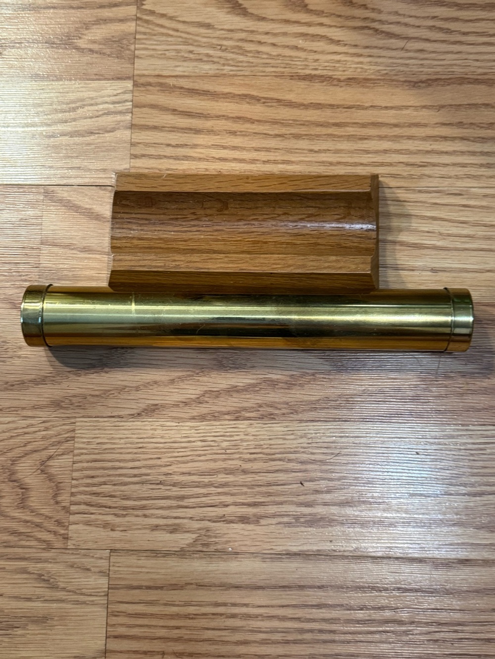 A vintage brass kaleidoscope for resting on a custom grooved wooden base